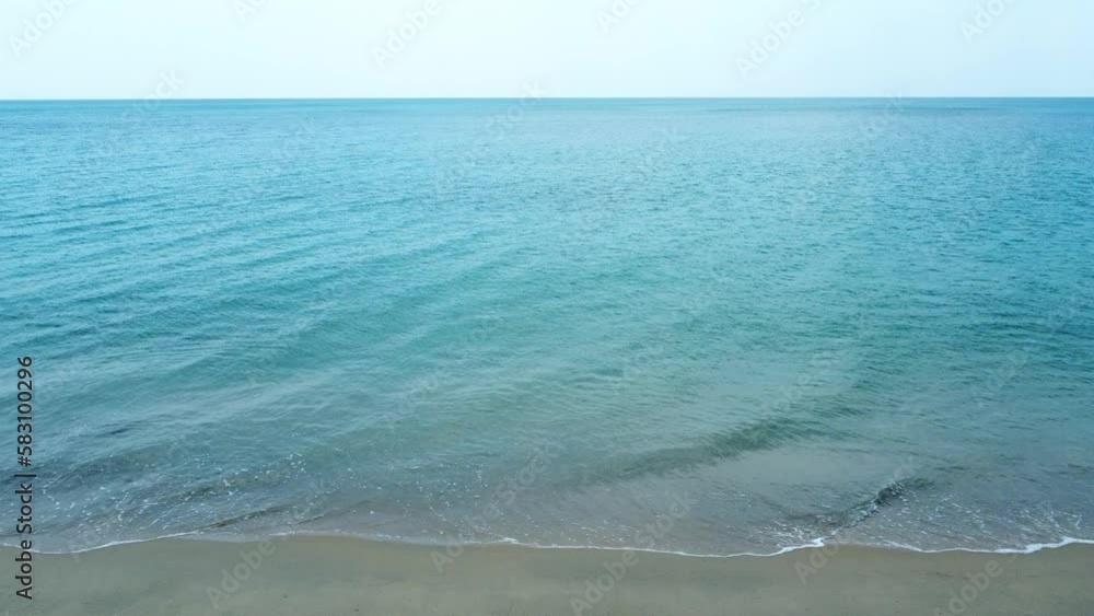 Bird's eye view of ocean waves crashing against an empty sand beach from above. Drone moving Bird's eye view of ocean waves crashing against an empty sand beach from above. Drone moving