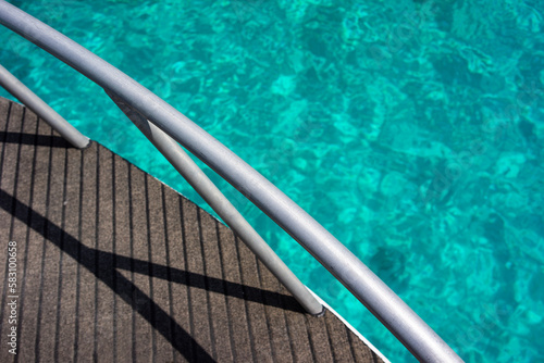 Boat side metal railing in the sea turquoise.