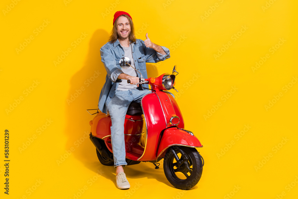 Full length photo of confident funny guy dressed jeans shirt thumb up driving vehicle isolated yellow color background Full length photo of confident funny guy dressed jeans shirt thumb up driving vehicle isolated yellow color background