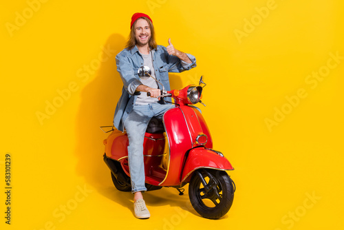 Full length photo of confident funny guy dressed jeans shirt thumb up driving vehicle isolated yellow color background © deagreez
