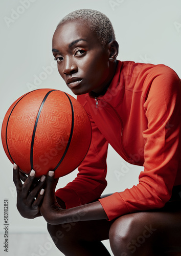 Ill outplay you any day. Studio shot of an attractive young woman playing basketball against a grey background. photo