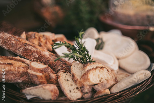 The board is set up on a long buffet table. The cheeses are arranged alongside sliced cured meats, fresh grapes, and berries, and the warm glow of the overhead lights adds to the overall ambiance 