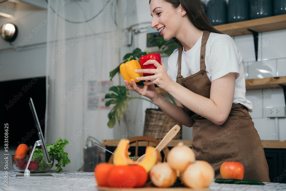 woman using laptop computer searching and learning for cooking healthy food from fresh vegetables and fruits in kitchen room. woman using laptop computer searching and learning for cooking healthy food from fresh vegetables and fruits in kitchen room.