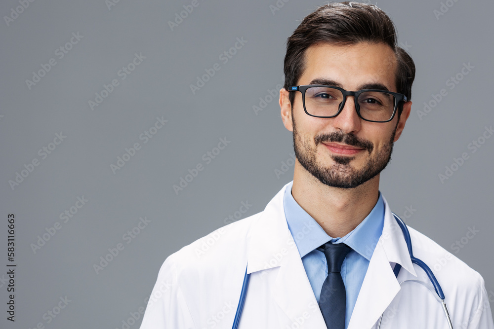Male doctor in a white coat and glasses for vision and a stethoscope looks at the camera smile with teeth dentist on a gray isolated background, copy space, space for text, health Male doctor in a white coat and glasses for vision and a stethoscope looks at the camera smile with teeth dentist on a gray isolated background, copy space, space for text, health
