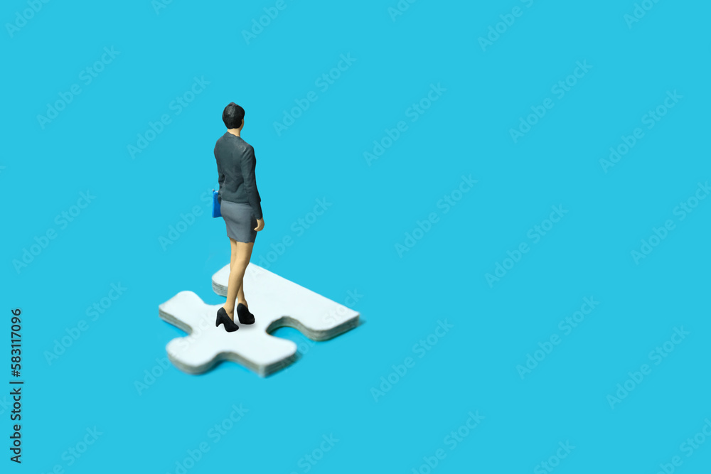 Miniature people toy figure photography. A businesswoman standing above missing piece of puzzle jigsaw. Isolated on blue background