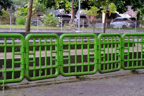 The iron fence painted green also functions as a gate that can be shifted to open and close.