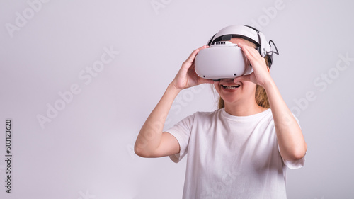 Surprised teen woman student use vr glasses and looks at empty space with gray background. Virtual gadgets for entertainment, work, free time and study. Virtual reality metaverse technology concept.