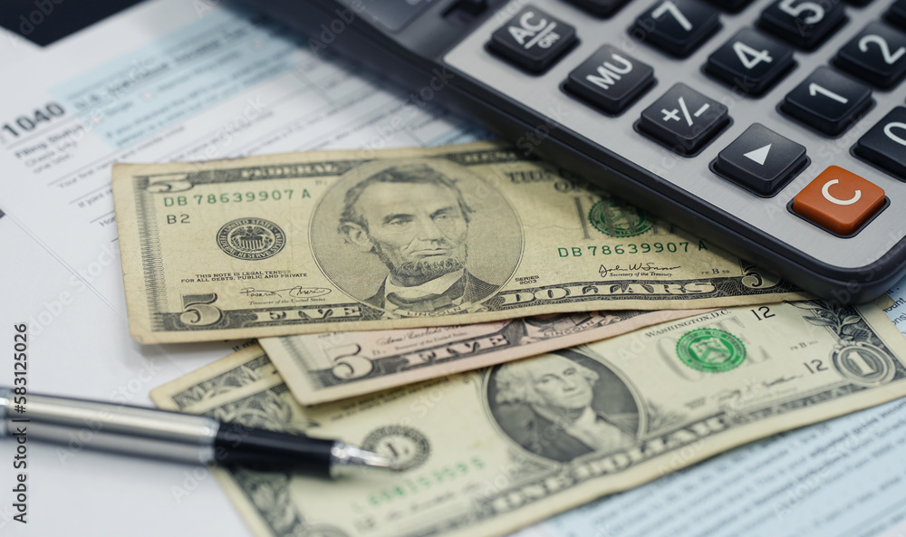Tax season concept. Tax planning and consulting service business. Pen, calculator, dollar banknote, and income tax return form for filling and calculating tax payments. Money and financial concept. Tax season concept. Tax planning and consulting service business. Pen, calculator, dollar banknote, and income tax return form for filling and calculating tax payments. Money and financial concept.