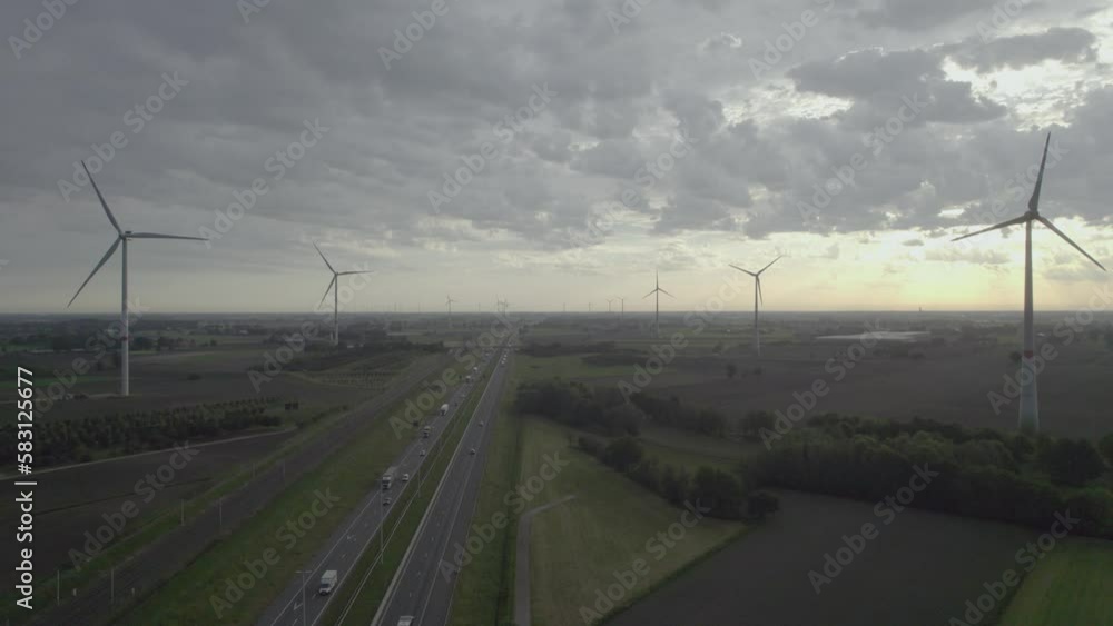 Panoramic aerial view on a windmill farm along a highway and railroad from drone. Cinematic aerial view of large wind turbines producing clean sustainable energy, clean energy future. Windmill farm in Panoramic aerial view on a windmill farm along a highway and railroad from drone. Cinematic aerial view of large wind turbines producing clean sustainable energy, clean energy future. Windmill farm in