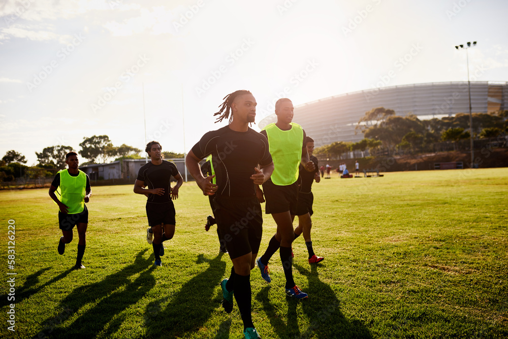 Fototapeta premium Doing laps keeps us fit. a diverse group of sportsmen warming up before playing rugby during the day.