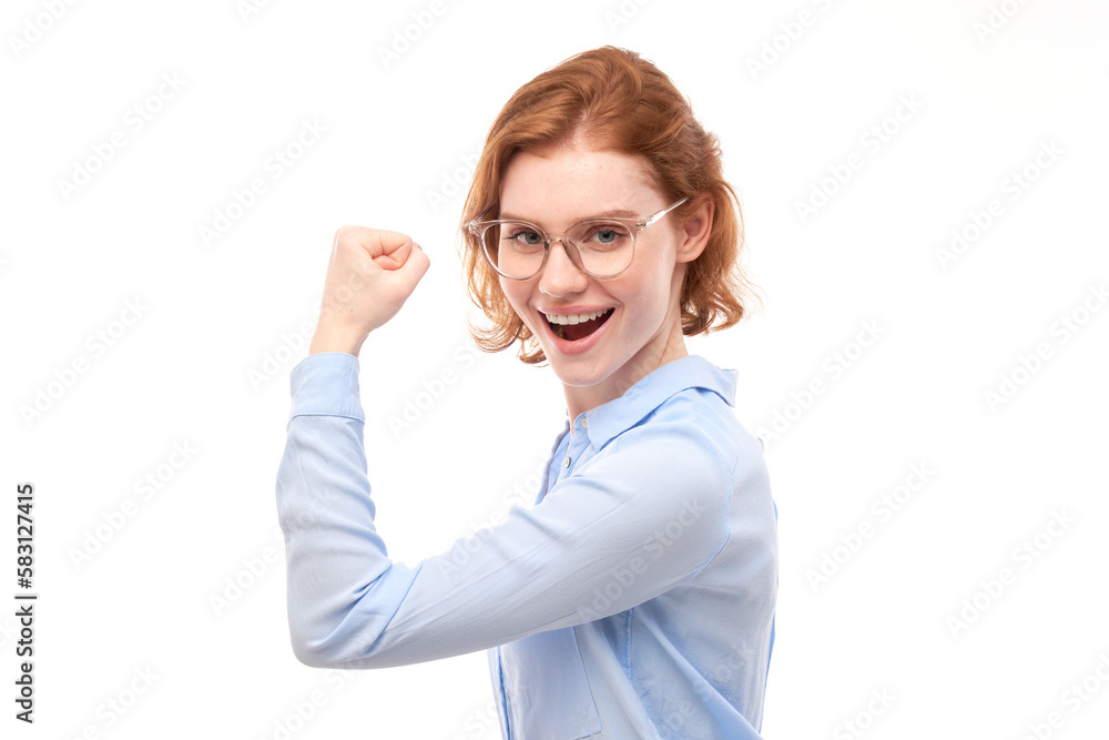 Portrait of young red-haired woman showing biceps, demonstrating girl power isolated on white background. Portrait of young red-haired woman showing biceps, demonstrating girl power isolated on white background.