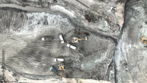 Excavator Working On Huge Mining Site, Loading The Trucks, Trucks Transport The Material, aerial view.