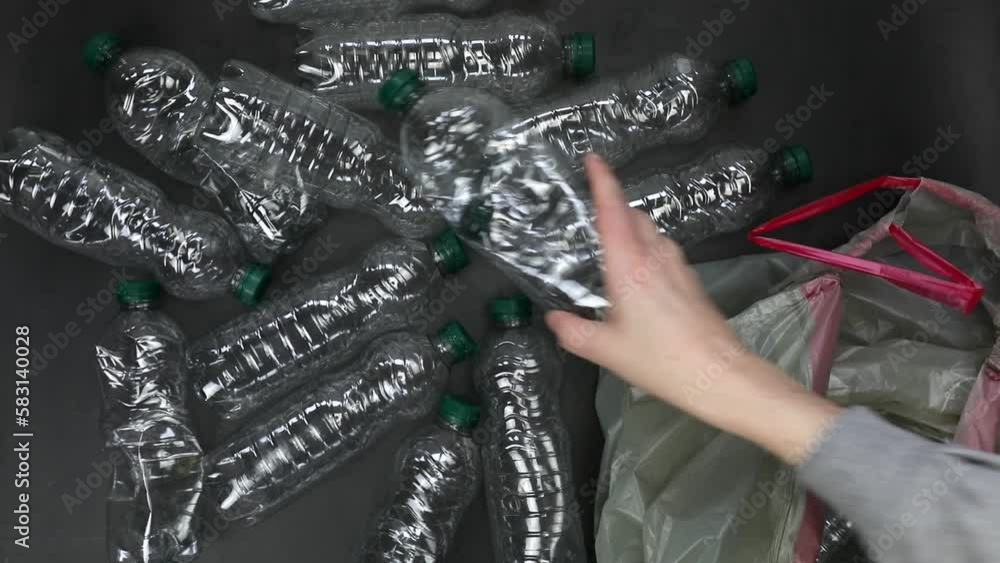 Hand getting plastic bottles to dispose in garbage bag ready to recycle