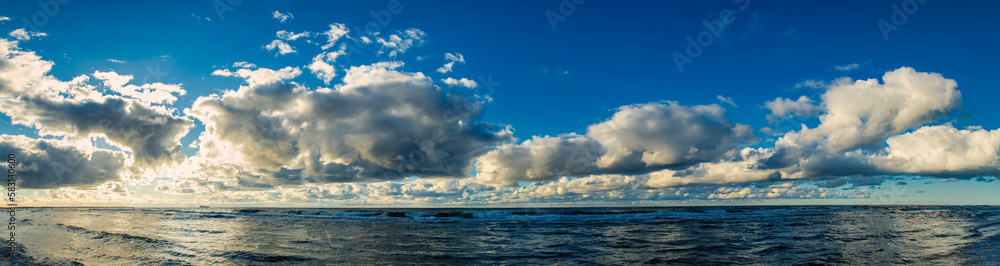 A panoramic view of the sea with a cloudy sky. Beautiful narrow background on the theme of sea vacation with clear water and serene blue sky.