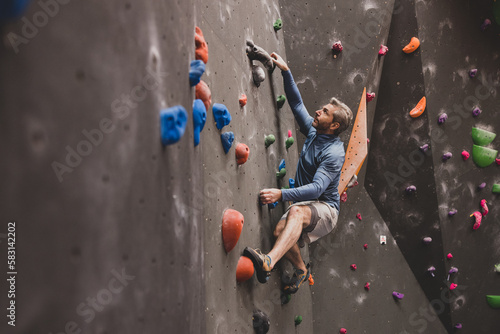 Mature male rock climber climbing a bouldering wall  photo