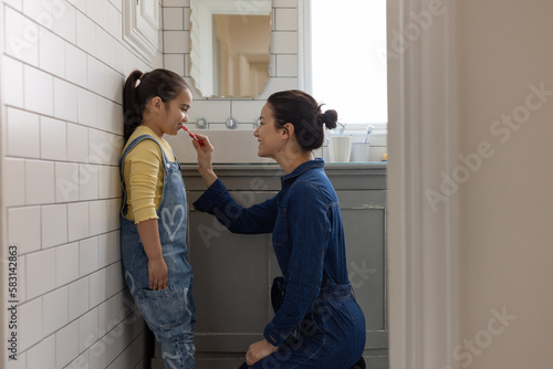 Mom helping daughter to brush her teeth before school in the morning 