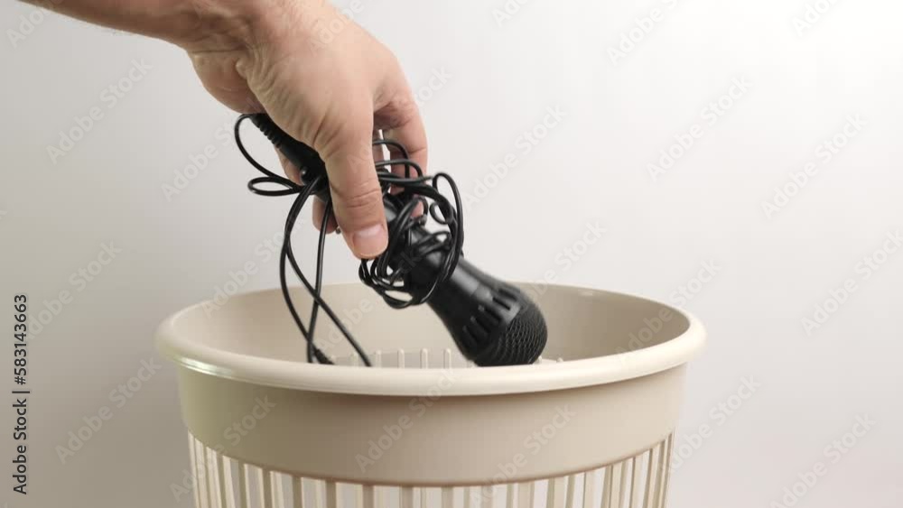 A broken microphone is thrown into the trash. Waste disposal and