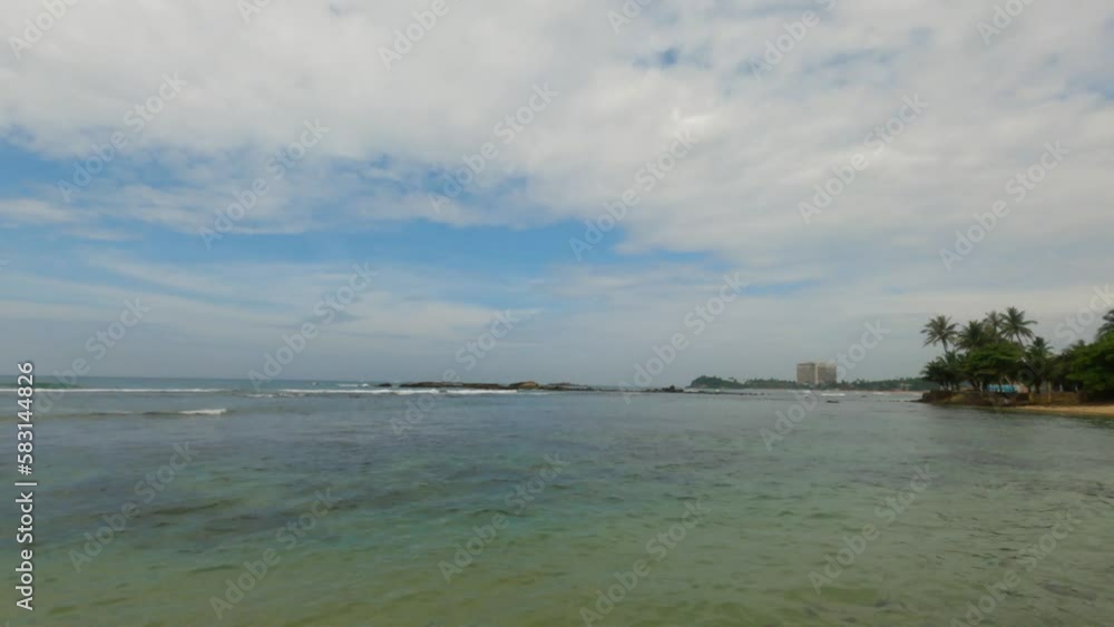 Traditional Sri Lanka seascape scene for travel or nature concept. Ocean waves with a foam splashing on a sand beach. Calm waves in sunny day Traditional Sri Lanka seascape scene for travel or nature concept. Ocean waves with a foam splashing on a sand beach. Calm waves in sunny day