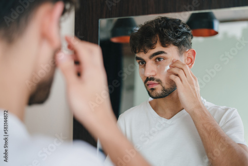 Young man applying under eye anti-wrinkle patches, doing morning facial procedures with hydrogel beauty product, skincare concept. Beauty treatment. Skin care