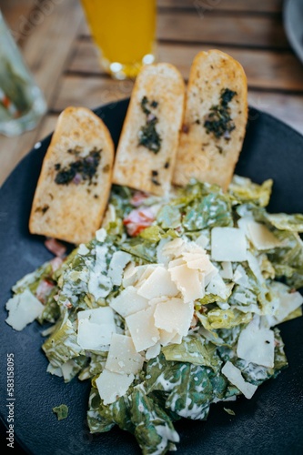 Vertical shot of a plate with gourmet ceaser salad and sliced bread photo