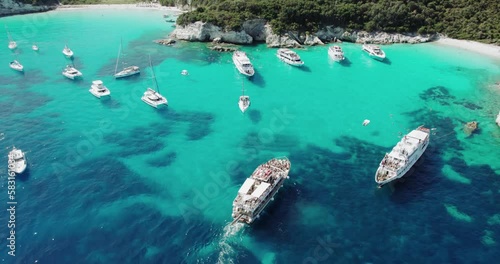 Antipaxos Island, Greece, with sandy beach, people swimming and yachts docked in the ethereal clear blue waters of the Ioanian island near Corfu photo