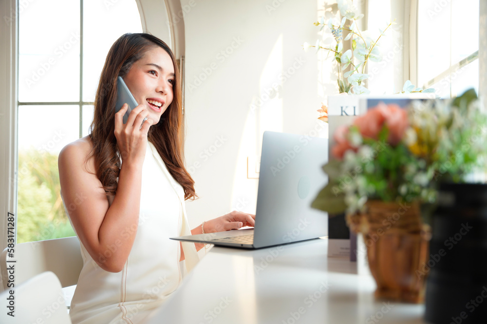 Asian woman with curly hair is working chatting with clients or colleagues via communication channels, telephone, internet with her laptop and mobile phone. Asian woman with curly hair is working chatting with clients or colleagues via communication channels, telephone, internet with her laptop and mobile phone.