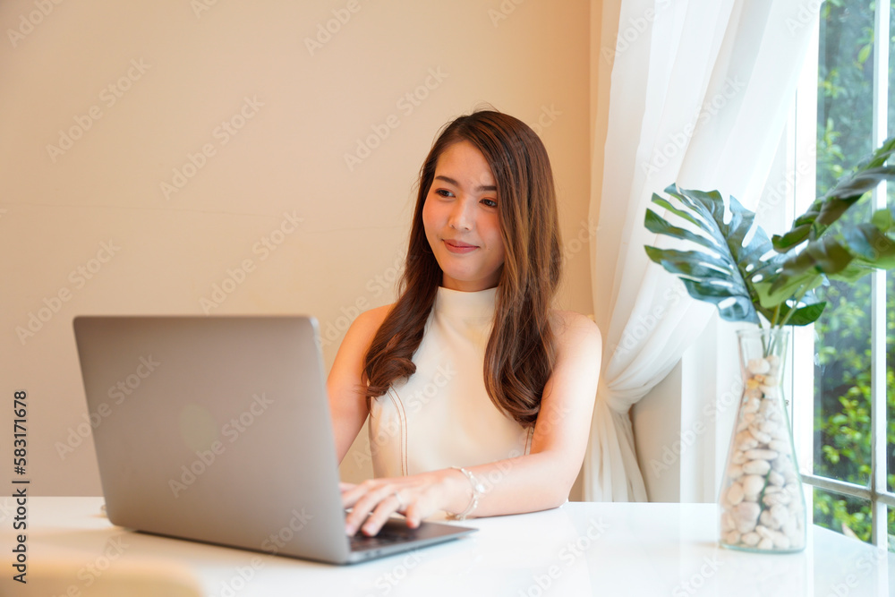 Asian woman with curly hair is working chatting with clients or colleagues via communication channels, telephone, internet with her laptop and mobile phone. Asian woman with curly hair is working chatting with clients or colleagues via communication channels, telephone, internet with her laptop and mobile phone.