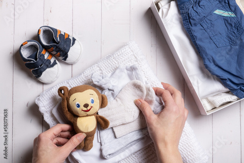 Female hands put children's clothes, shoes and toys into a donation box. Second hand, clothing recycling concept photo