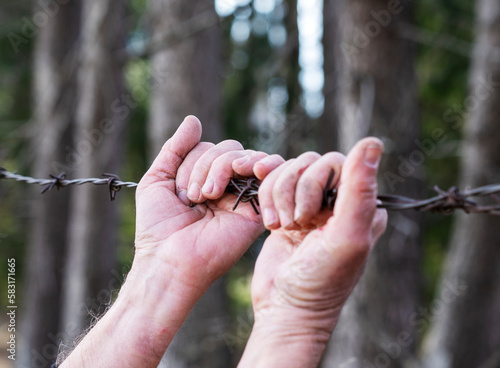 hands clasped on barbed wire