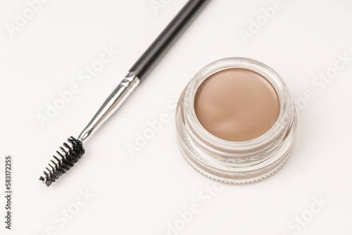 A brow pomade in blonde shade with brush isolated on a white background.
