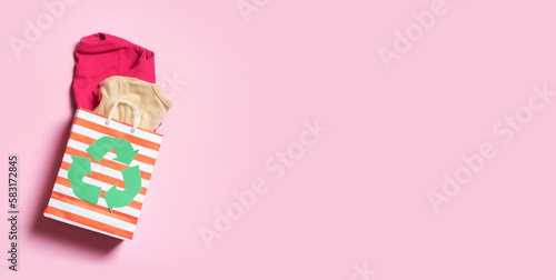 Children's clothes in shopping bag with a recycling symbol. Second hand, donation clothing recycling concept photo