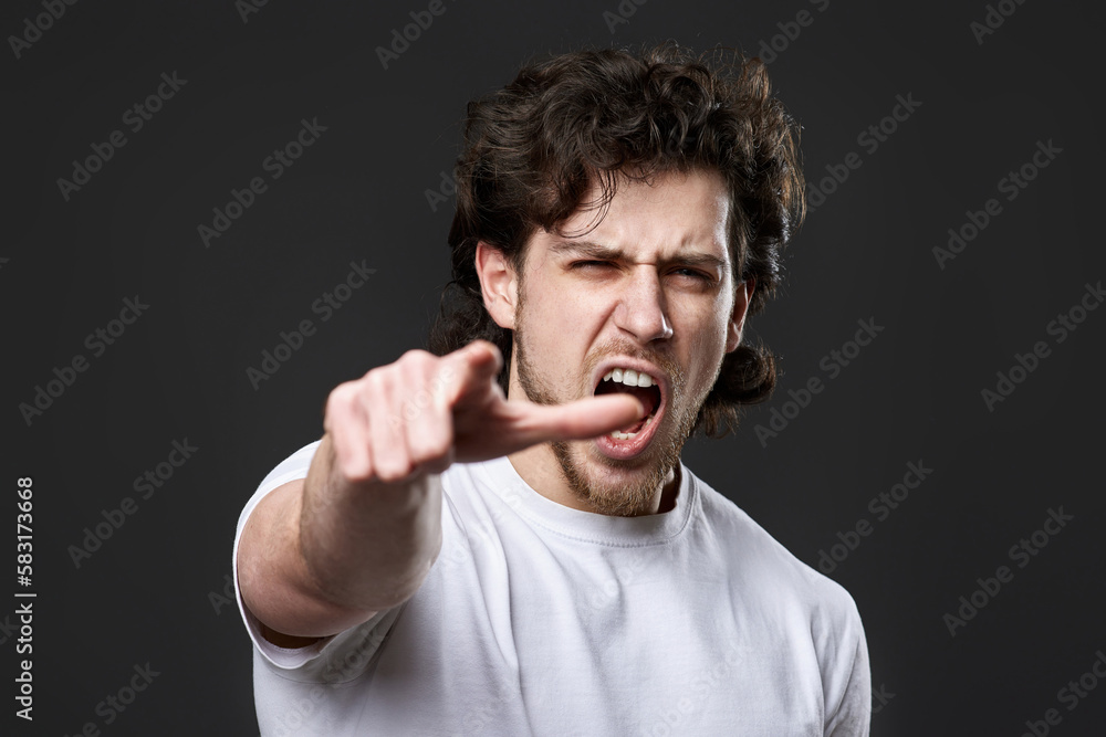 caucasian man pointing finger at you and the camera on dark gray background caucasian man pointing finger at you and the camera on dark gray background