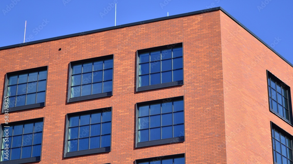 Naklejka premium A modern corporate building in the city. The blue sky is reflected in the buildings large glass windows. Glass facade.