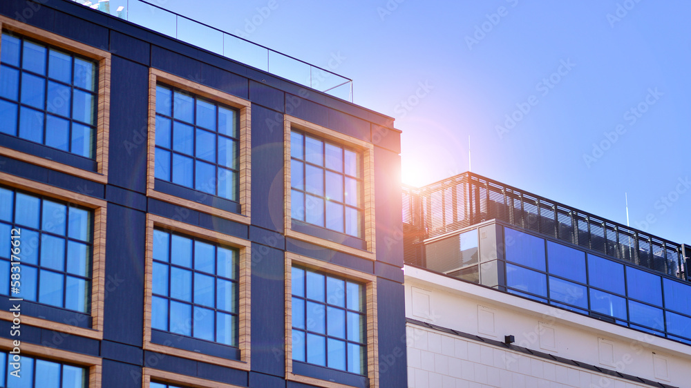 A modern corporate building in the city.  The blue sky is reflected in the buildings large glass windows. Glass facade.
