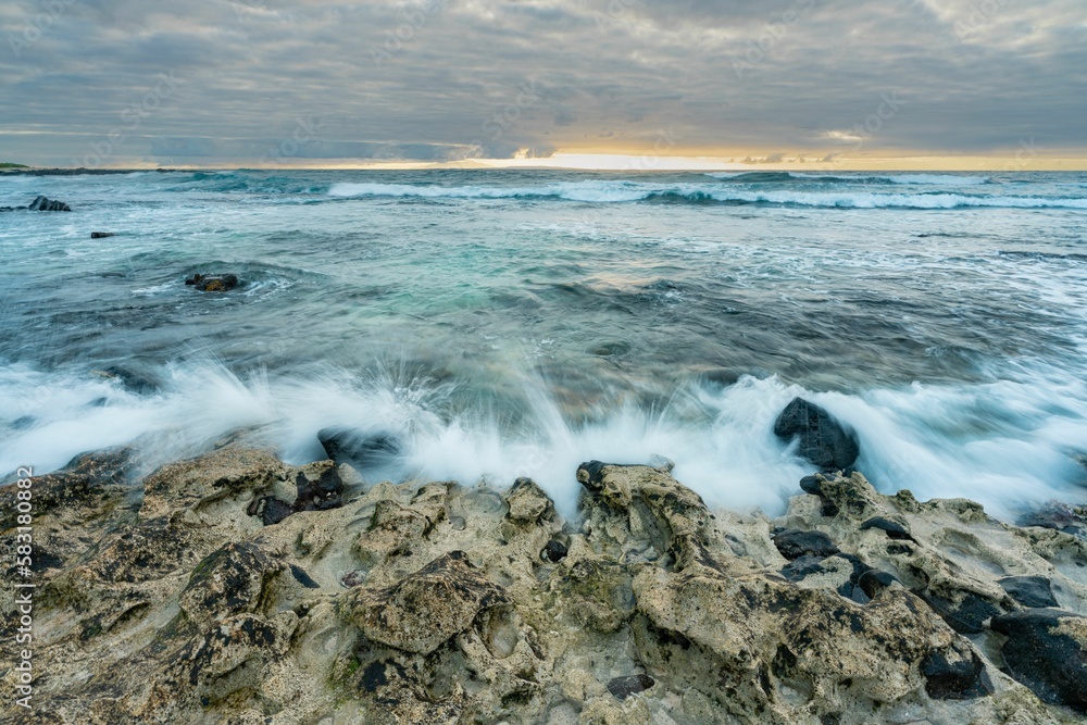 Long exposure shot of a sunrise over the rocky beach in Oahu, Hawaii. Long exposure shot of a sunrise over the rocky beach in Oahu, Hawaii.