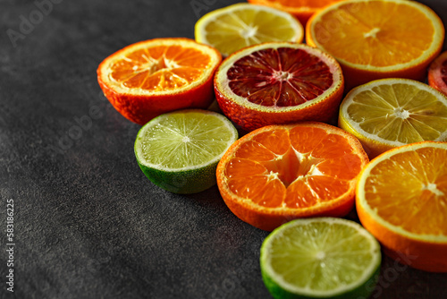 Citrus fruits cut in half, oranges, tangerines, lemons yellow, limes green, on dark background, selective focus