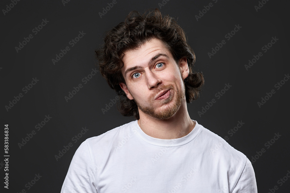 skeptic and nervous man in white t-shirt on dark gray background skeptic and nervous man in white t-shirt on dark gray background