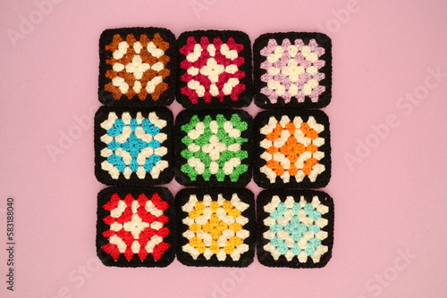 Close-up overhead view of nine crochet squares on a pink background photo