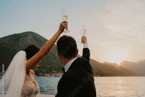 bride and groom newlyweds drinking champagne wine on boat on wedding day sunset romantic boho 