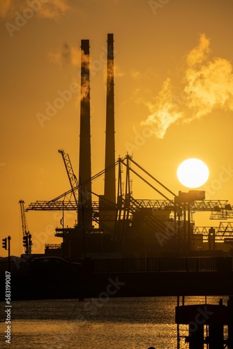 Vertical shot of an industrial site surrounded by water during a breathtaking sunset