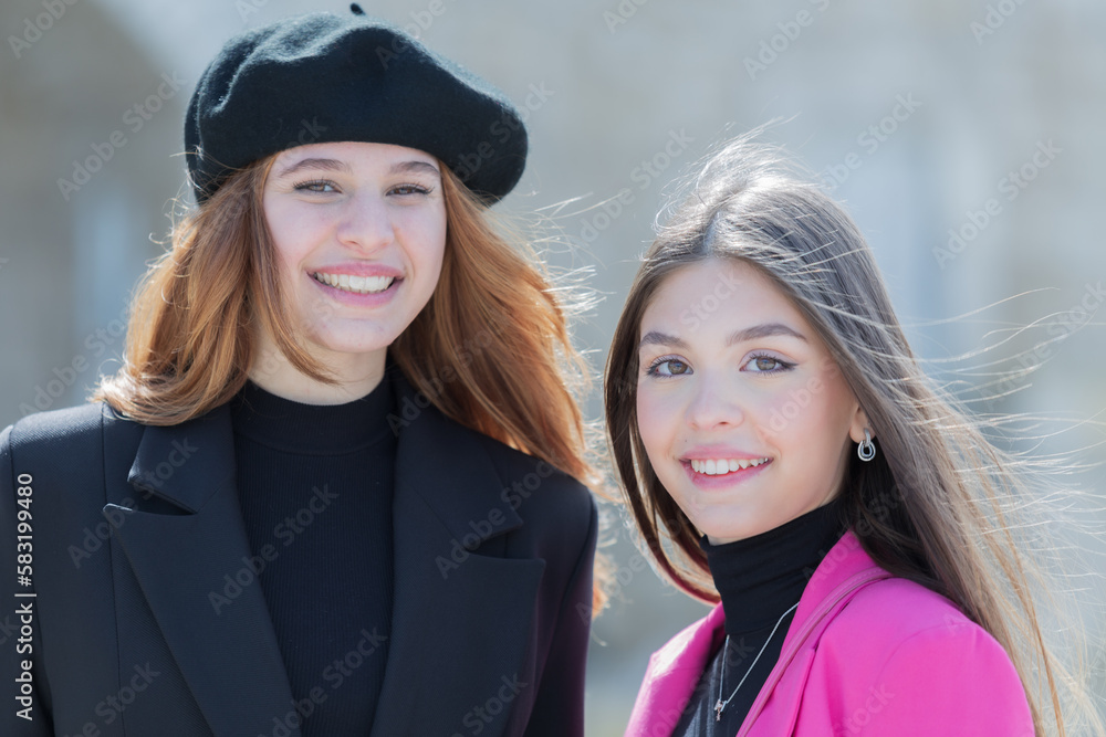 Two beautiful girls in the foreground outdoors against the sky, the brunette with a black hat and a very young girl with long hair Two beautiful girls in the foreground outdoors against the sky, the brunette with a black hat and a very young girl with long hair