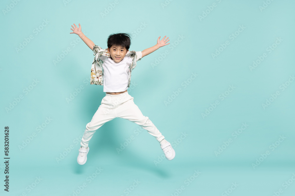 Asian little boy in flower pattern summer outfits jumping isolated on green background, Five years old Asian little boy in flower pattern summer outfits jumping isolated on green background, Five years old