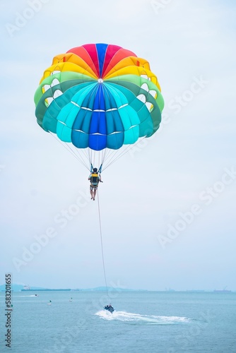 Man parasailing near the coast of the sea, vertical shot