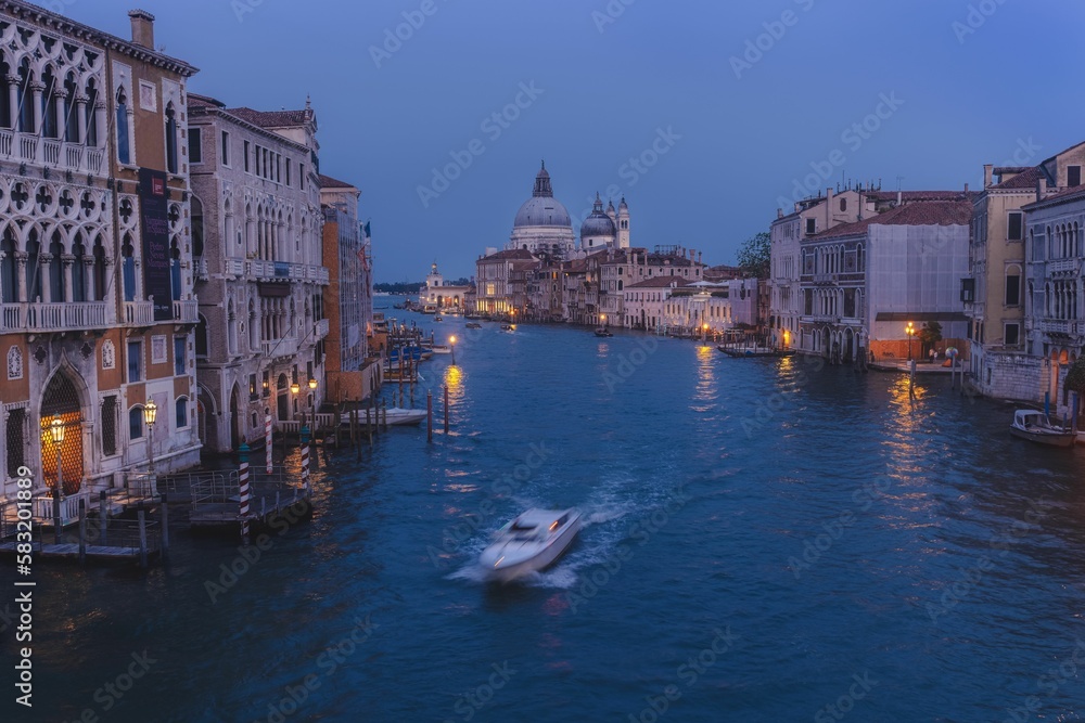 Aerial view of a boat sailing on the canal at night in Venice, Italy