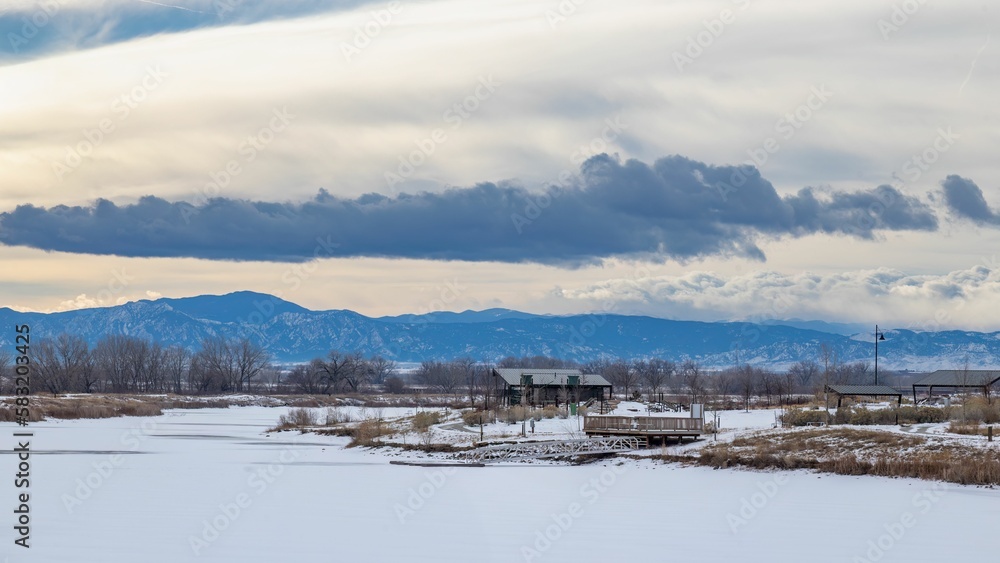 View to Colorado front range in winter with ice covered lake and park in foreground