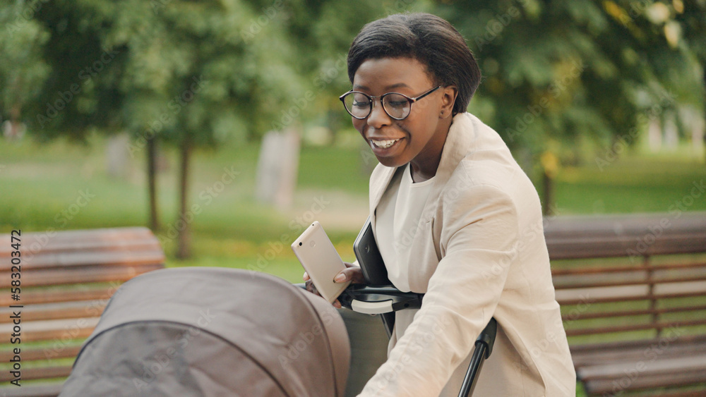 Obraz premium Young working mother taking care of baby in stroller, work-life balance, parenting