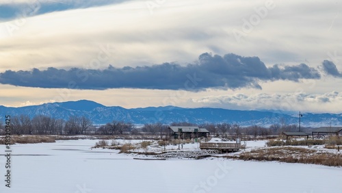 View to Colorado front range in winter with ice covered lake and park in foreground