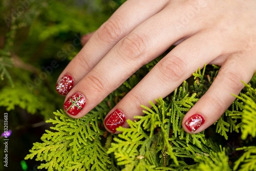 Closeup of red nail manicure design with snowflake on Christmas tree