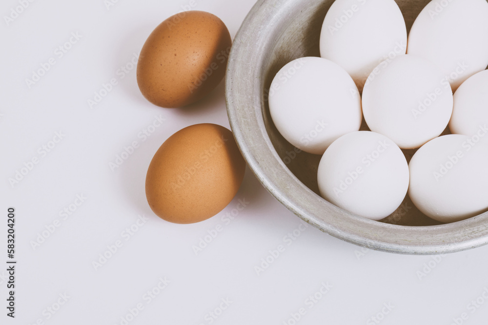 Brown eggs on bright background and white eggs in metal bowl. Close up, selective focus. Concept scene. Brown eggs on bright background and white eggs in metal bowl. Close up, selective focus. Concept scene.
