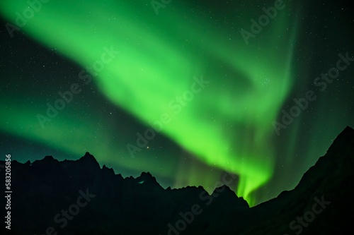 Scenic view of Northern Lights over silhouettes of maountains photo